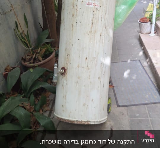 אדם מחזיק דוד שמש ישן בחצר